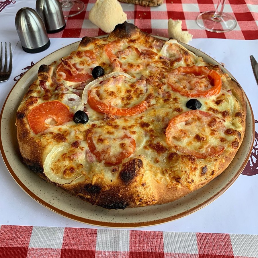 Pizza au feu de bois servie sur nappe vichy au restaurant Le Bonséjour à Verdun