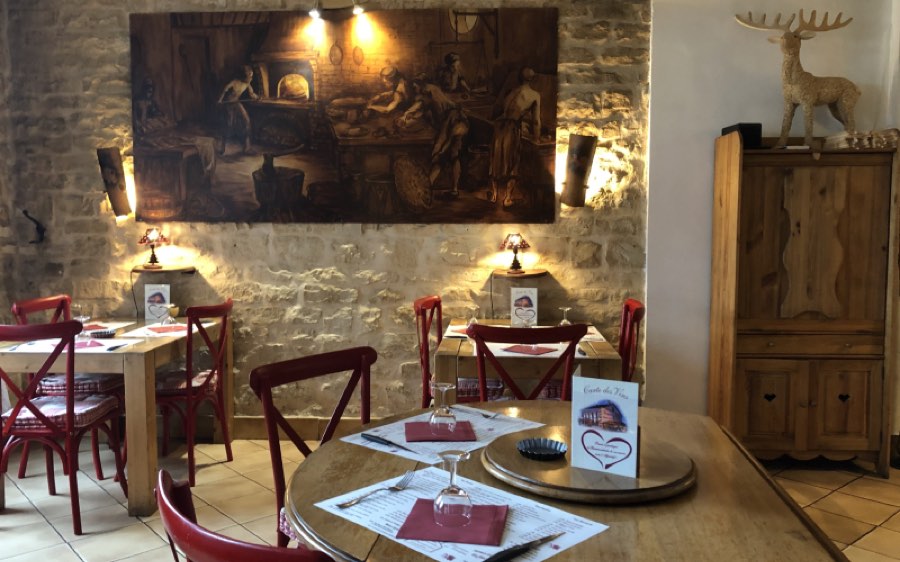Salle du restaurant Le Bonséjour à Verdun : pierres apparentes et chaises rouges